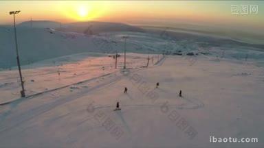 在滑雪场的斜坡上滑雪和单板滑雪的航拍广角镜头，背景是日出